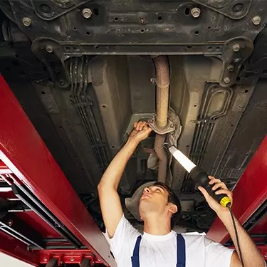 MOT ANNUAL ASSESSMENT - mechanic assessing the underside of a car
